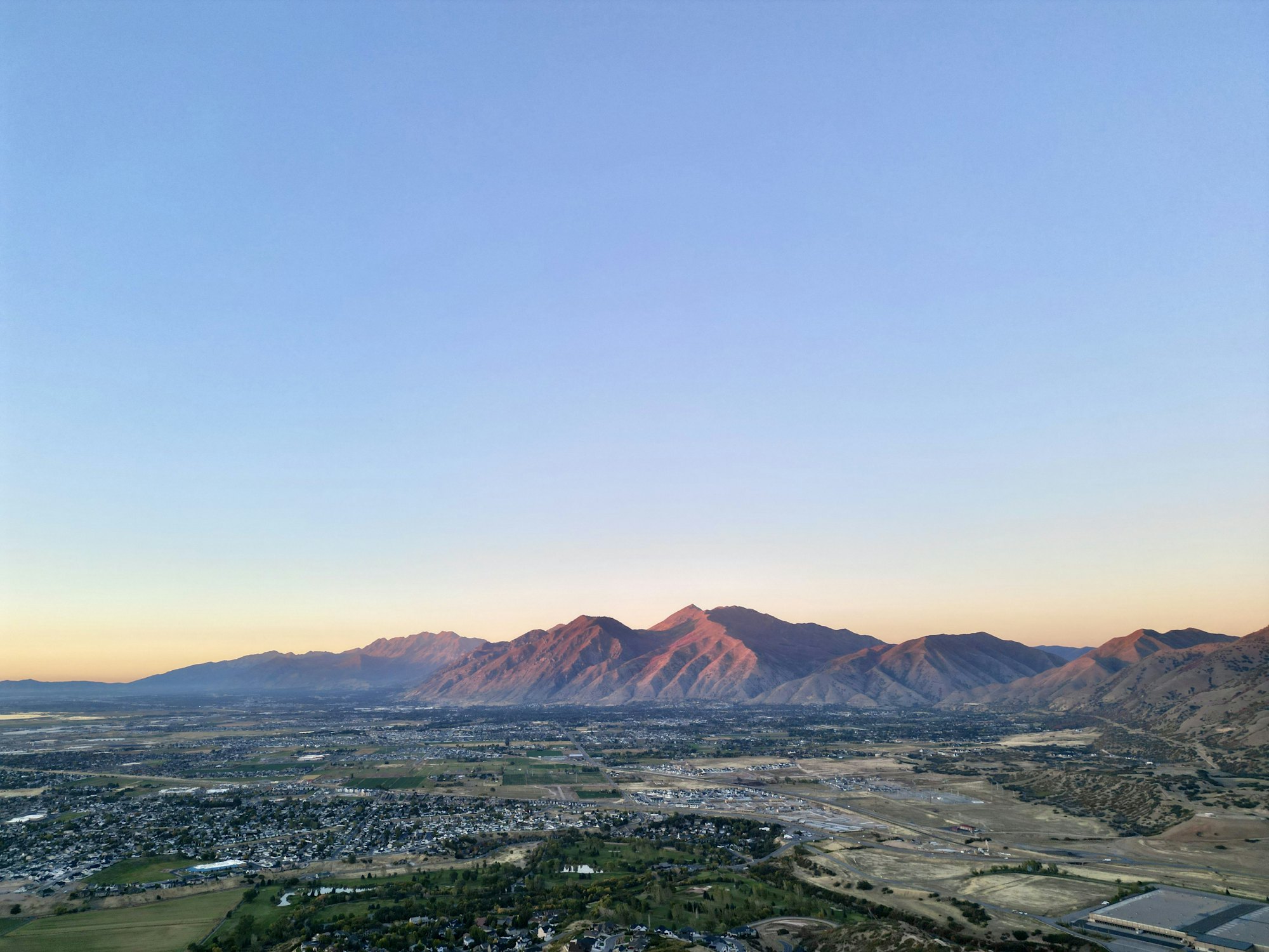 Utah Valley at sunset from above, with the mountains catching the last light.
