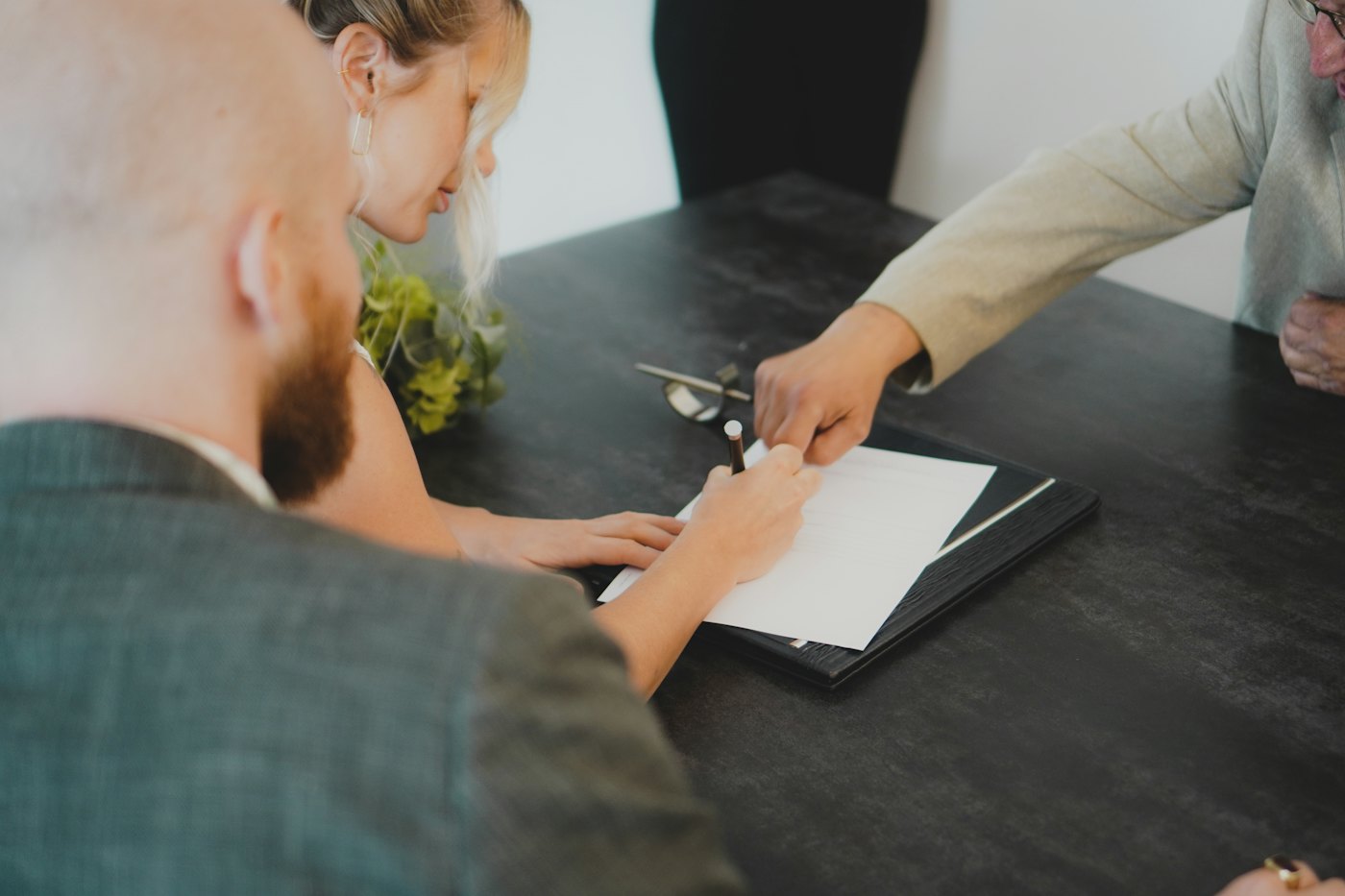 Two people signing a document together at a desk.