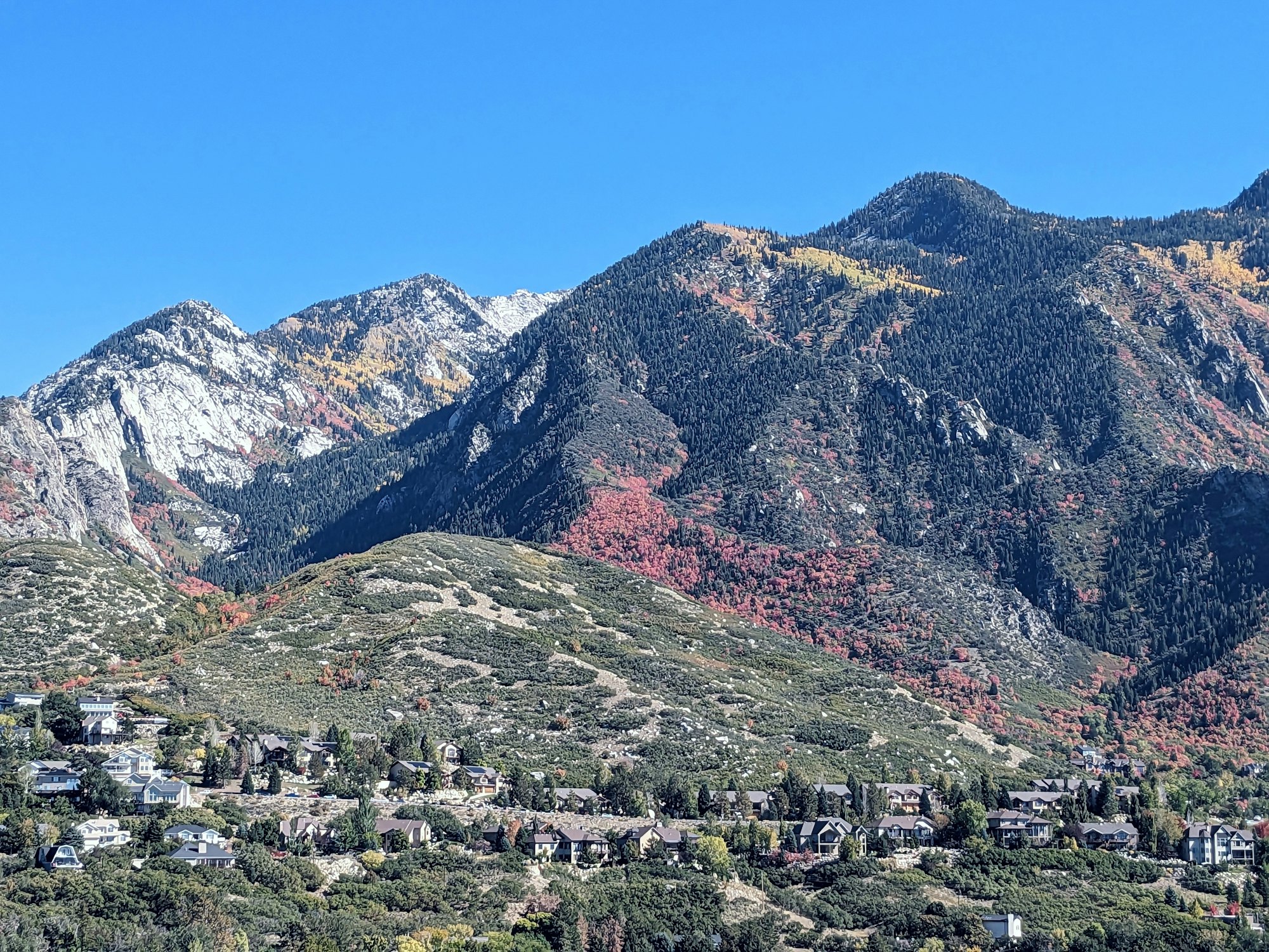 Homes at the foot of the Wasatch Range in autumn, with snow on the peaks.