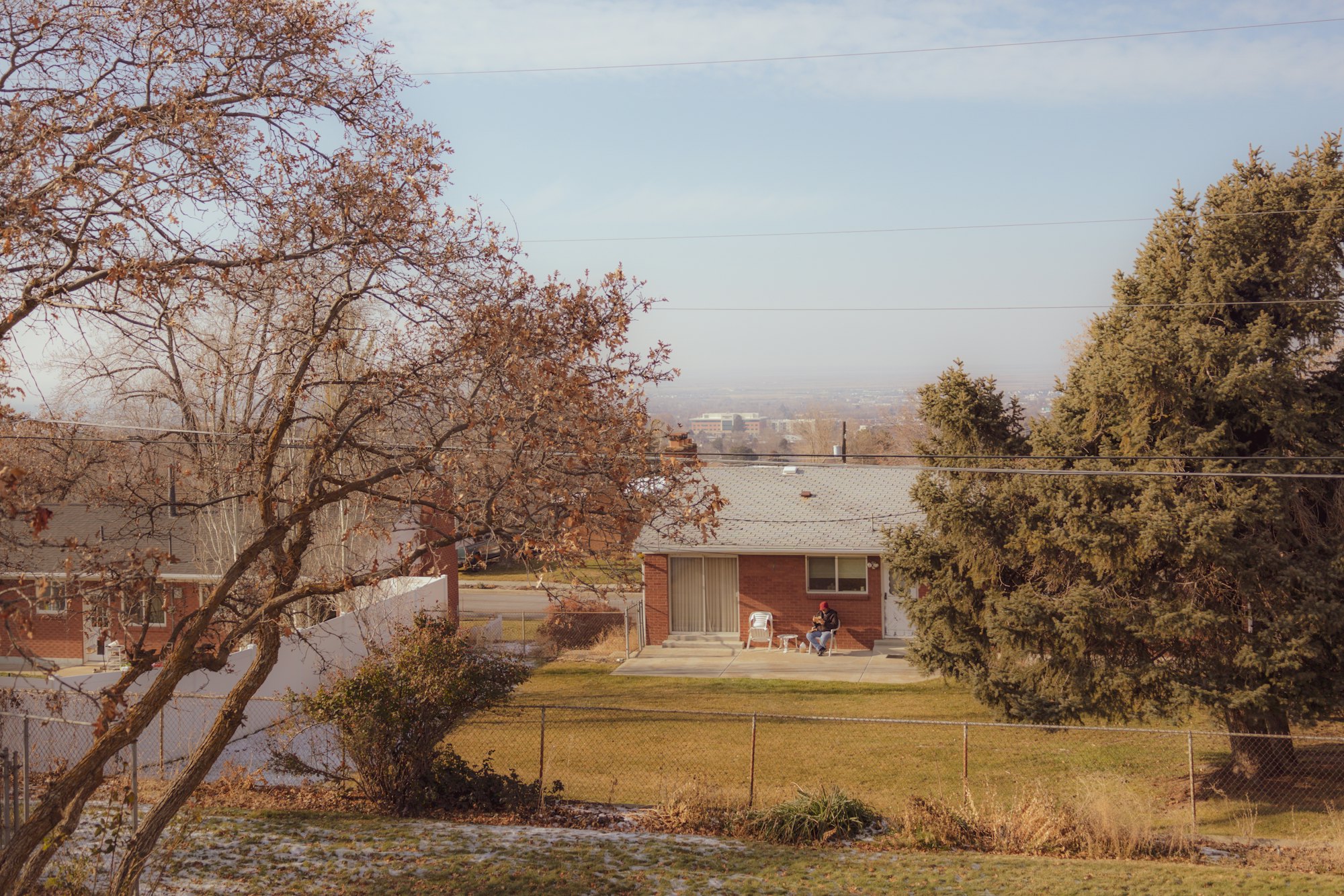 A brick home seen across its yard on an autumn evening, with the valley beyond.
